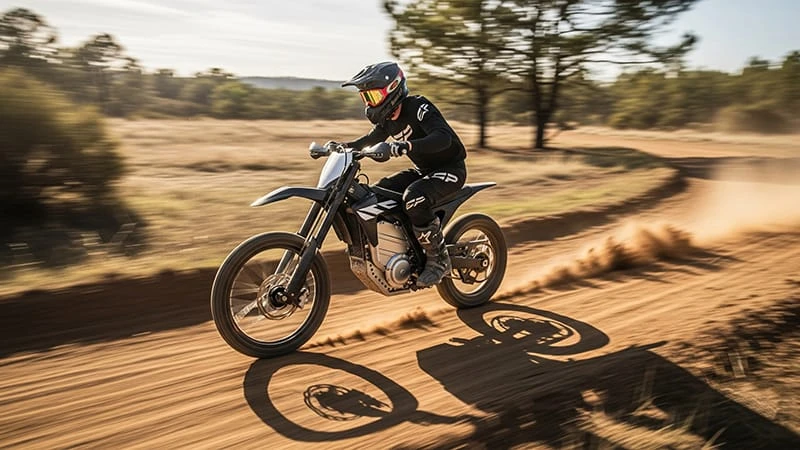 An electric dirt bike moving at high speed on an open trail, creating a motion blur effect.