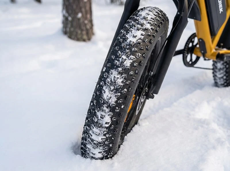 Close-up of the POLEEJIEK F6 4-inch fat tire gripping packed snow, illustrating the concept of flotation and traction for winter riding.