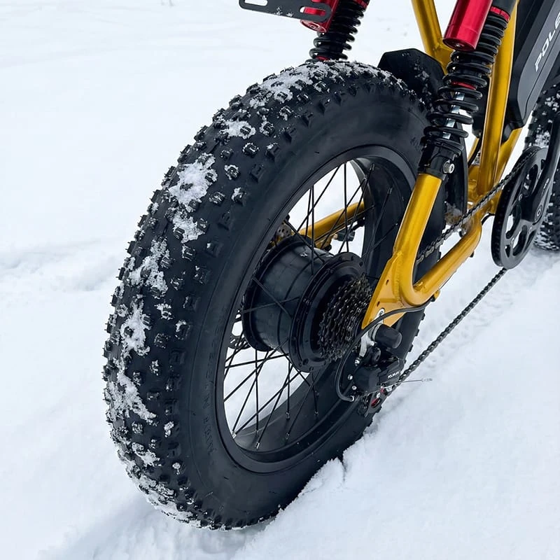 Close-up of a 4-inch wide off-road ebike tire leaving a deep tread pattern in fresh snow, illustrating flotation and grip.